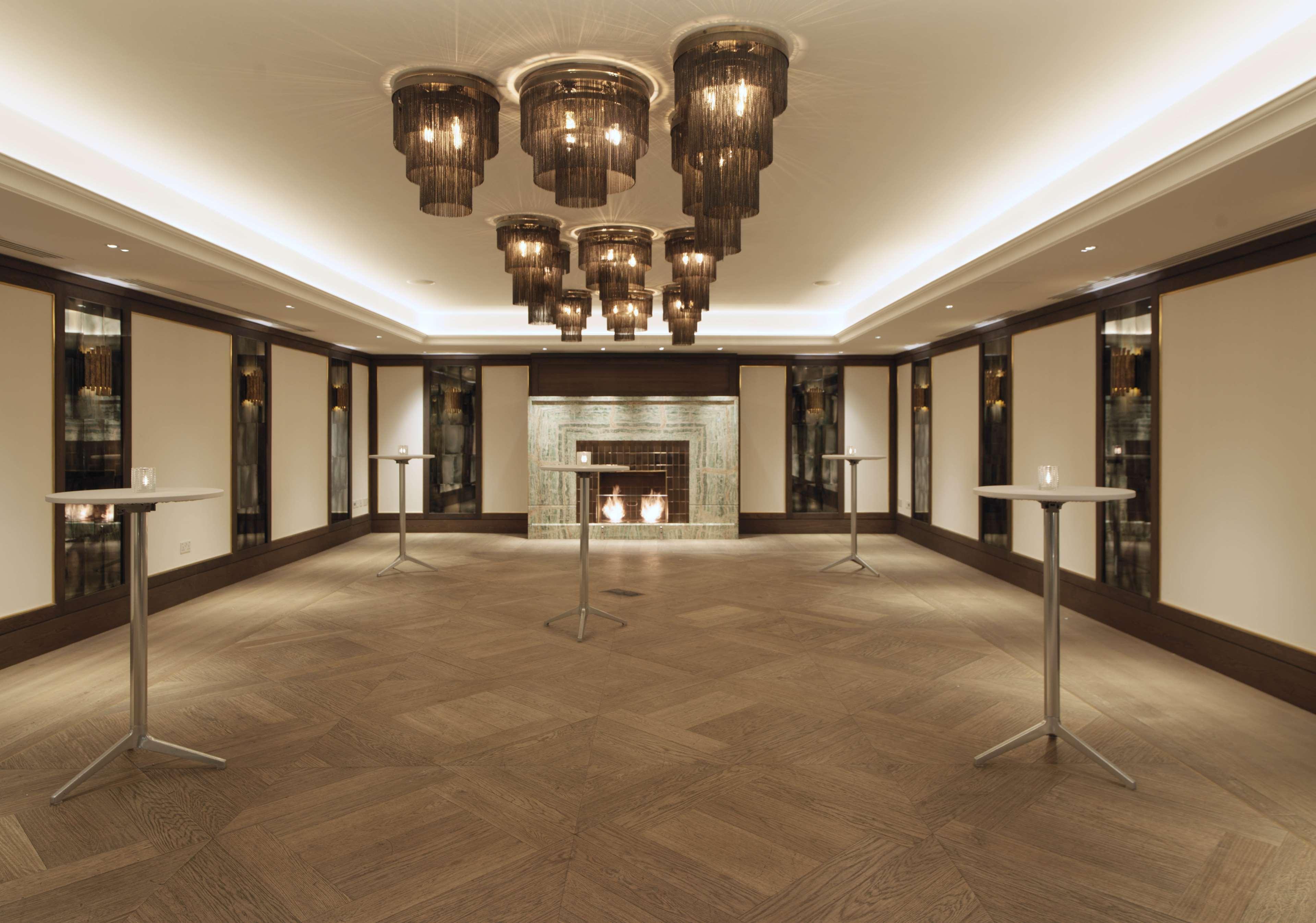 The May Fair, A Radisson Collection Hotel, Mayfair London Exterior photo The photo showcases an elegant indoor space, likely designed for events or gatherings. The room features a sophisticated lighting arrangement with several modern pendant chandeliers hanging from the ceiling. There are minimalistic tall tables scatter